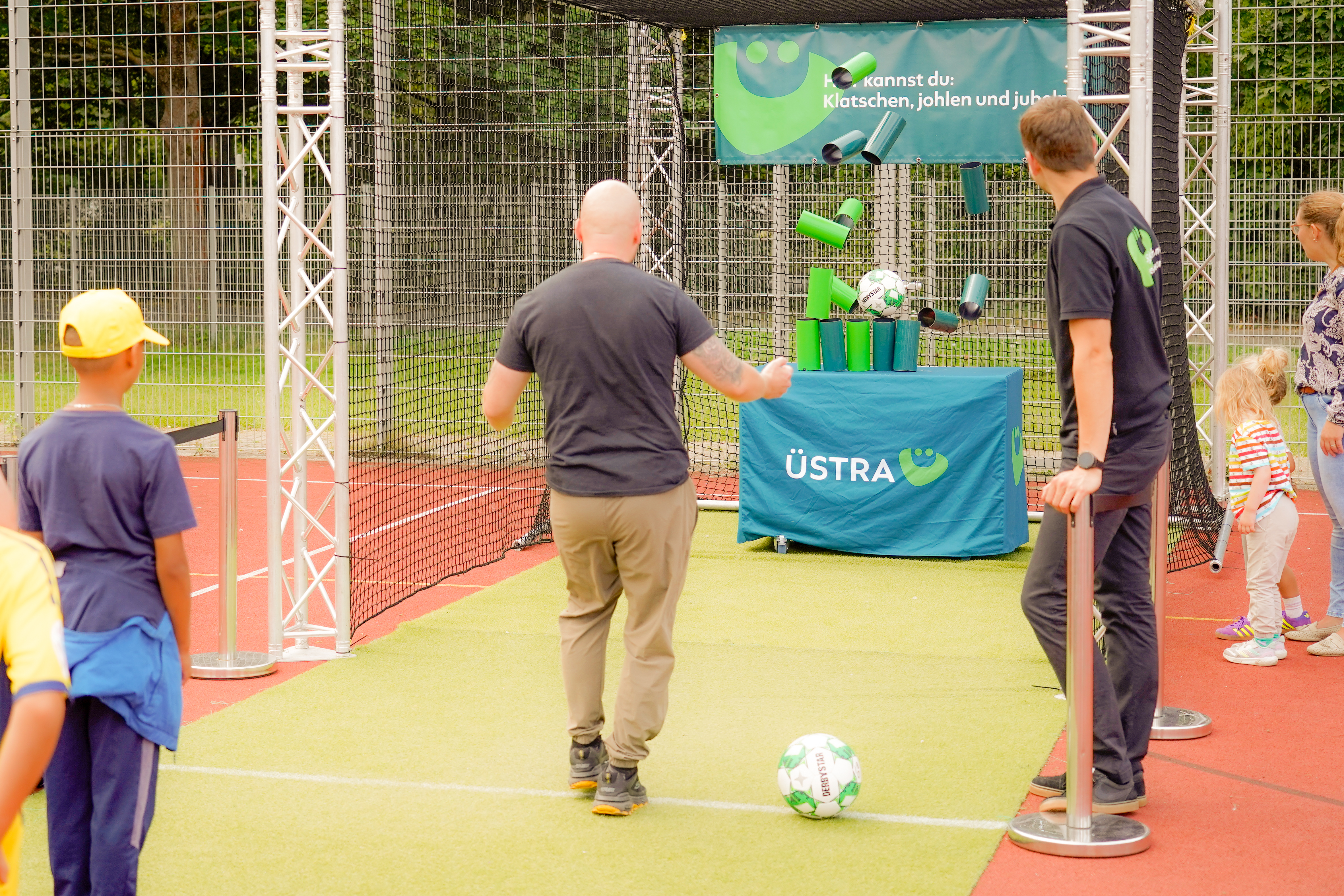 Ein Mann schießt bei einer Veranstaltung im Freien einen Fußball auf ein Ziel, während die Zuschauer zusehen.
